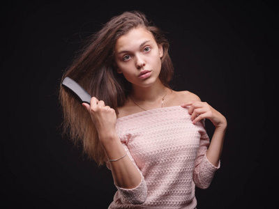 悲伤的女人抱着乱了头发的黑色背景。一撮头发女孩手上。头发损失概念。复制空间