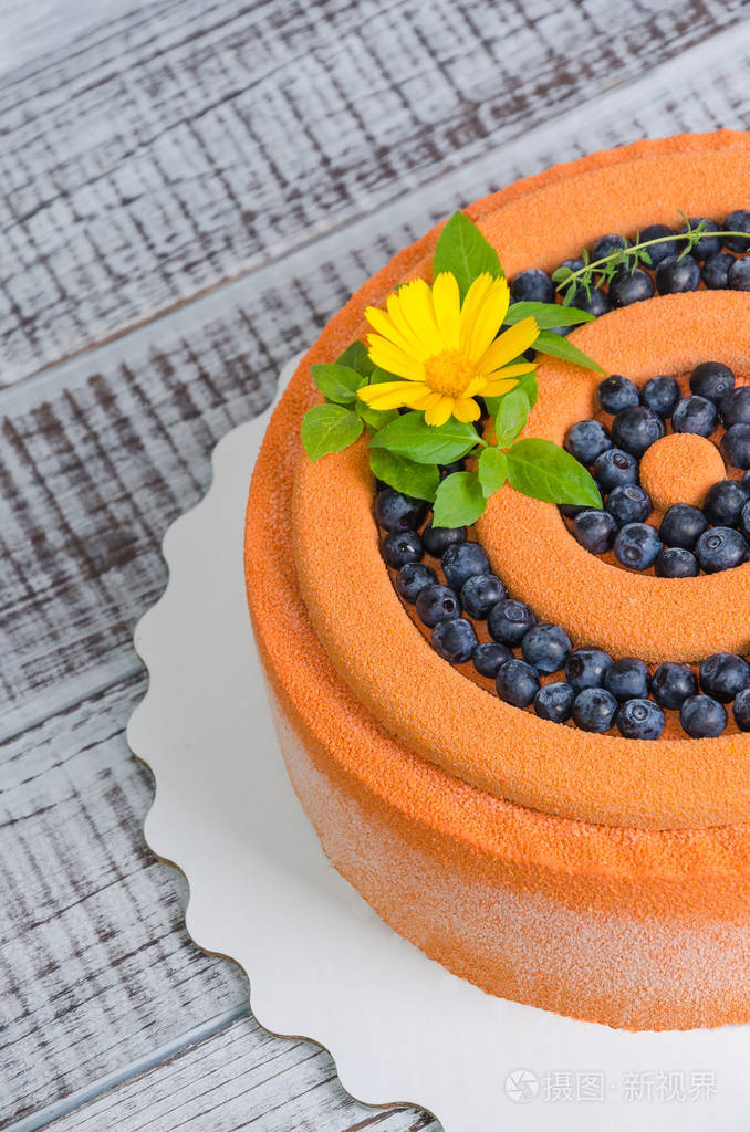 橙色的巧克力丝绒蛋糕用鲜花, 蓝莓和罗勒