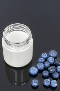 在玻璃罐和黑色的背景垂直蓝莓酸奶