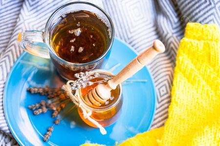 杯红茶和罐蜂蜜蓝板和针织的围巾