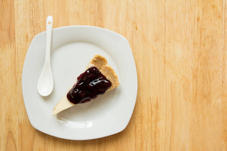 蓝莓乳酪蛋糕上白盘子里用勺子木桌背景
