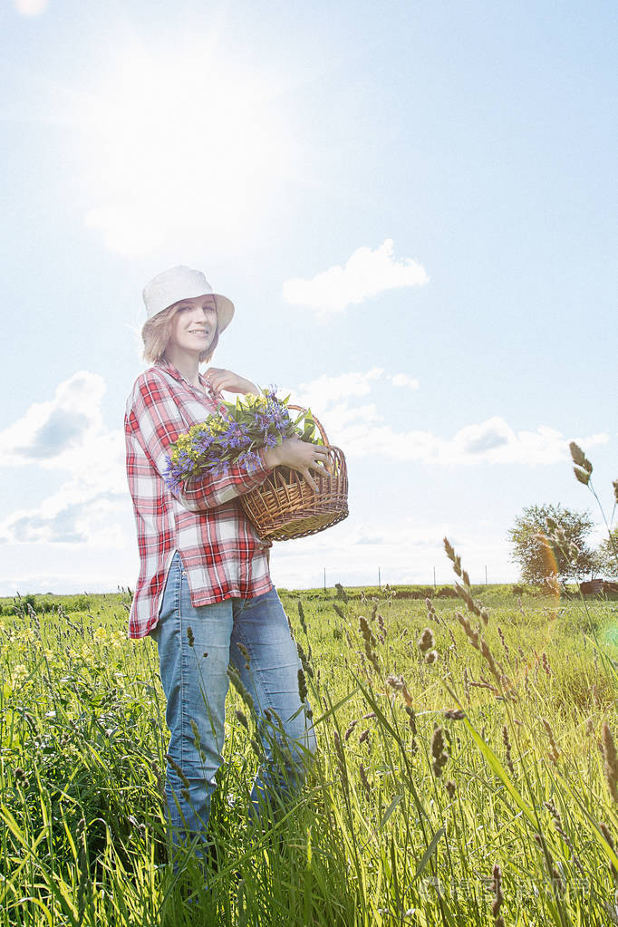 田野里的一个女孩用篮子收集花田里的花