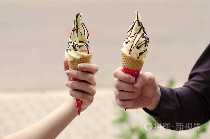 男孩和女孩抱着两个冰淇淋与巧克力始终浸没在硅片背景模糊的手的特写