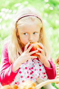 美丽的小女孩在花园里咬苹果的肖像