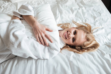 幸福的年轻女人，穿着浴袍躺在床上
