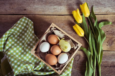 郁金香和木制背景上的鸡蛋。复活节背景