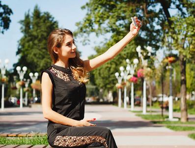 制作自拍照在智能手机上一个美丽的年轻女人的画像