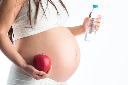 怀孕的妇女抱着新鲜苹果和水