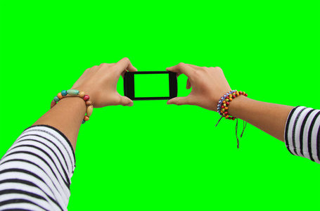 年轻的女孩的手移动智能手机在绿色屏幕上