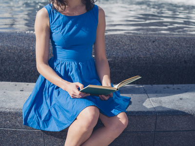 阅读在城市喷泉旁的年轻女人