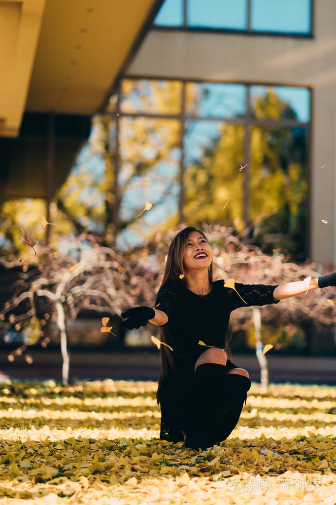 幸福年轻的女人在阳光明媚的秋日公园内笑玩树叶性格开朗的美丽女孩在