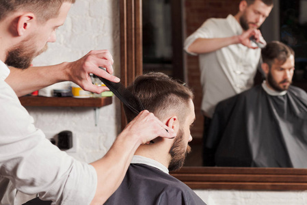 年轻英俊的理发师在理发店理发的有魅力的男人
