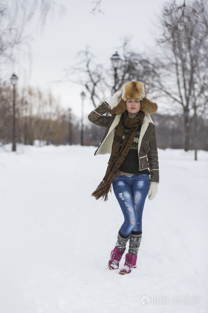 在严寒的冬季公园的美丽女孩.户外活动.纷飞的雪花