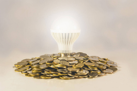 能源节能灯泡和周围的成堆的硬币。金融 保存和思想理念