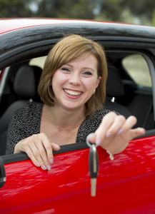 有魅力的女人微笑骄傲坐在驾驶员座位上抱着和车钥匙示新汽车购买和租赁