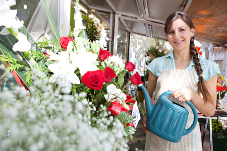 浇水的植物和花朵在她店里的花店女人