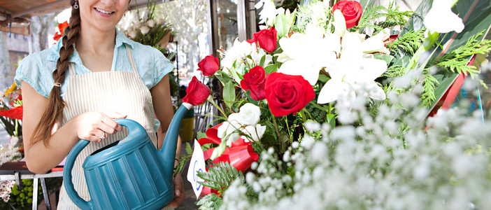 浇水的植物和花朵在她店里的花店女人