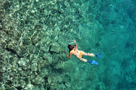 年轻女子在透明的浅海浮潜