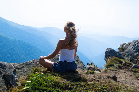 年轻的金发美女,美丽的山景观进行冥想照片