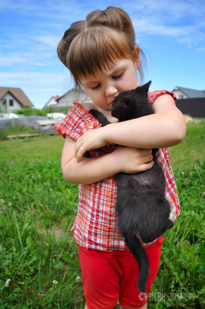 一个可爱的小女孩与小小猫,女孩玩上自然背景的猫的室外肖像照片-正版