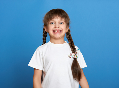 快乐的失去的牙齿女孩画像，工作室拍摄在蓝色背景