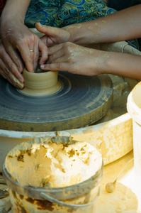 一名教师教的学生如何从陶工车轮上的粘土烧造陶器的手