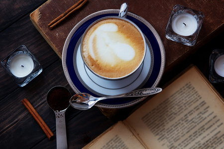 咖啡成分与旧书 白色茶蜡烛 银勺 咖啡粉和肉桂对深色木制背景