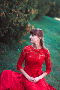 年轻漂亮的女孩，在一件红色的连衣裙草坐