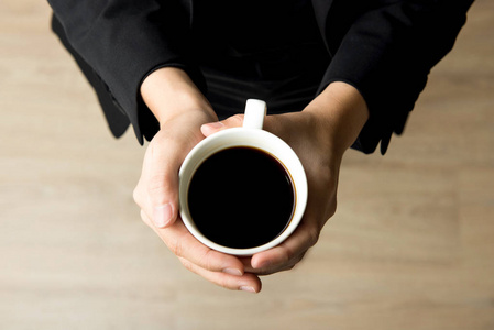 女人手里拿着杯咖啡与黑咖啡顶视图