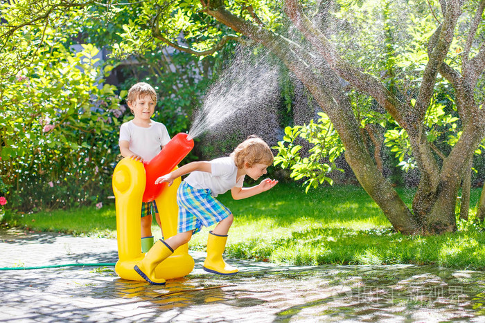 两个小孩子玩的橡胶软管和水在夏天