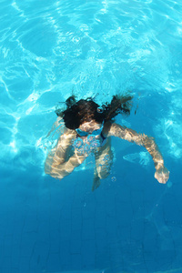 年轻女孩潜水，在池的蓝色水