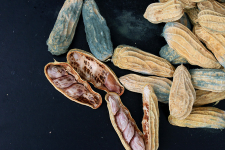 在黑色背景上发霉的花生大堆照片