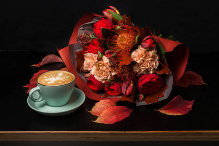 在黑色背景上的卡布奇诺咖啡和花卉组成