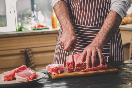 人在家庭厨房里木菜板上削减新鲜一块牛肉