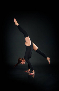 女子体操运动员显示出在黑暗背景下的运动技能