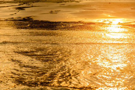 金色的光线反射水波在海洋和沙滩日落。纯的金音