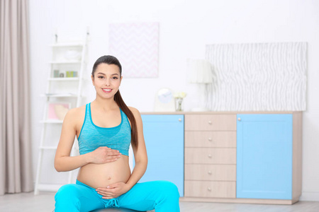 年轻的孕妇，在家里训练。健康概念