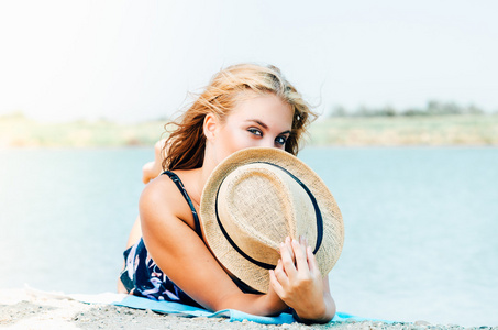 帽子捂着嘴的海滩上的年轻女子