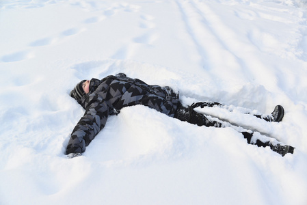 十几岁的男孩躺在雪中