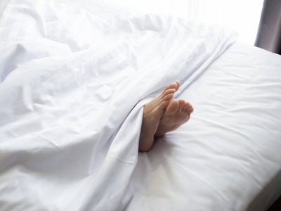 在白色的床 room.feet 的一名年轻女子躺在床上熟睡中的女人脚靠拢