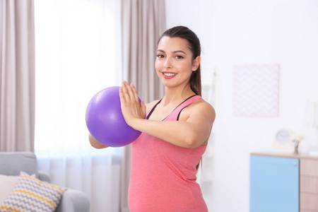 年轻的孕妇，在家里训练。健康概念