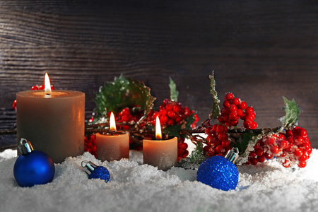 燃烧的蜡烛和花楸木背景上的雪图片
