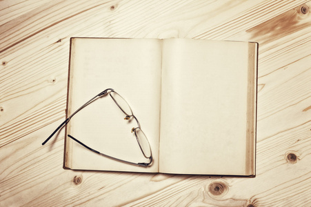 眼镜和木制背景上的书照片