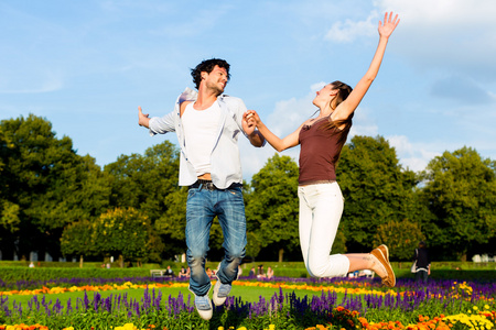 旅游对夫妇在公园在阳光下跳跃照片