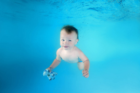 小男孩用玩具潜水水下在游泳池里