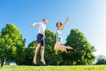 夫妇在公园草坪上跳跃的爱情