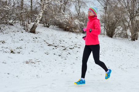 冬天在公园跑步 幸福的女人跑慢跑在雪 户外运动和健身概念