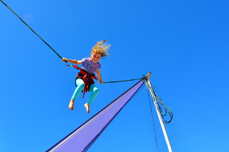 床上蹦在蹦床上的小女孩照片