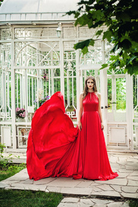 美丽的女人，在红色的晚礼服，在春天的花园户外