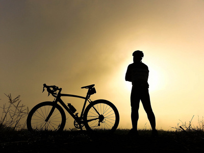在小山上风车骑自行车的人站在小山上看着阳光和放松照片